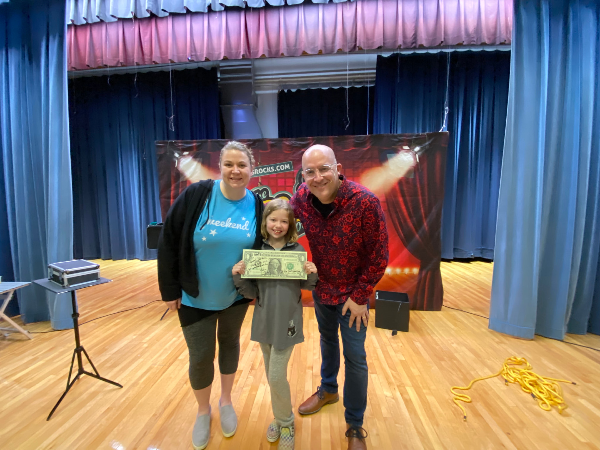 Tim with a mom and daughter volunteering on stage at Husmann