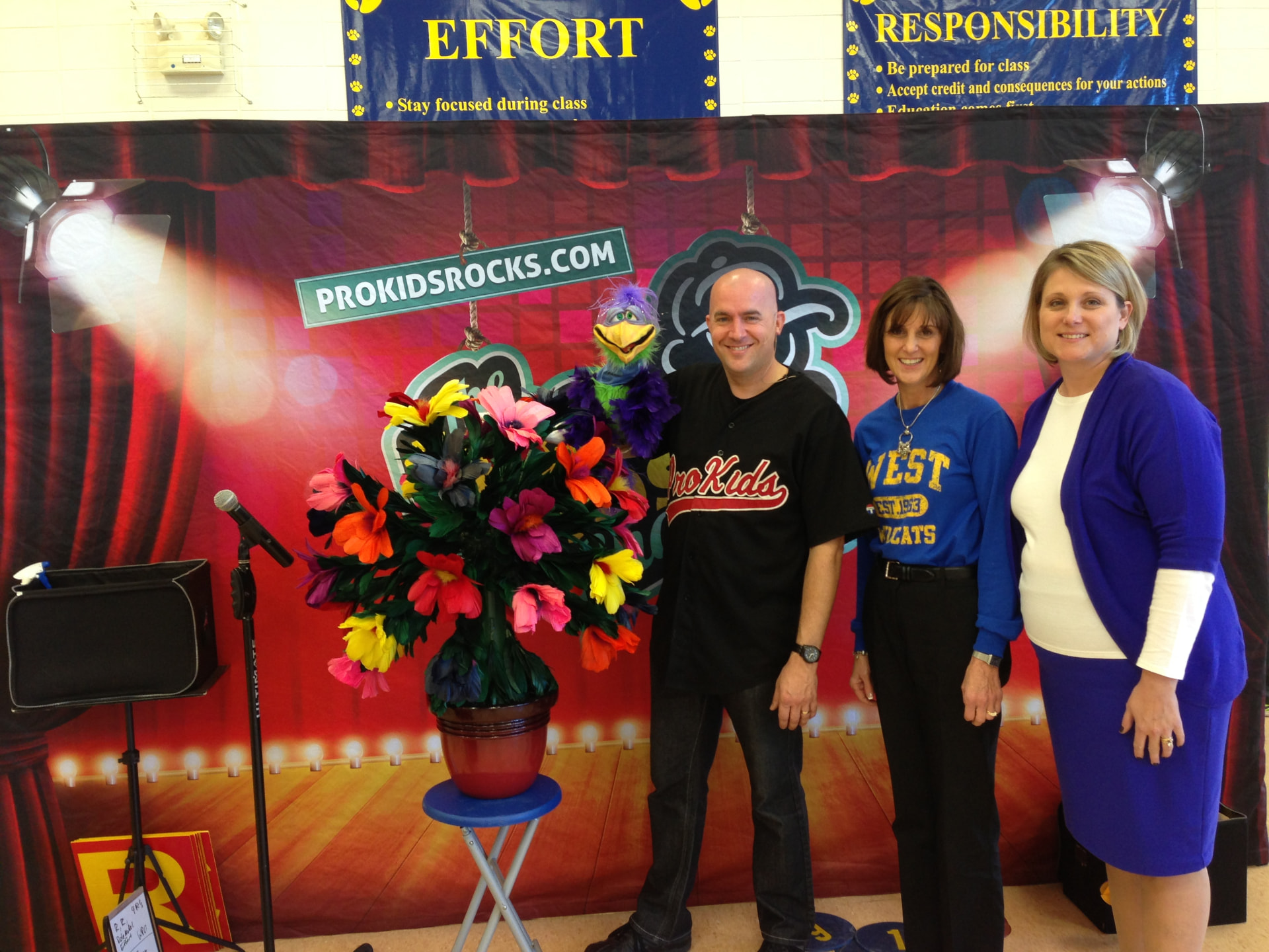 Tim with West Elementary staff in front of Effort and Responsibility banners