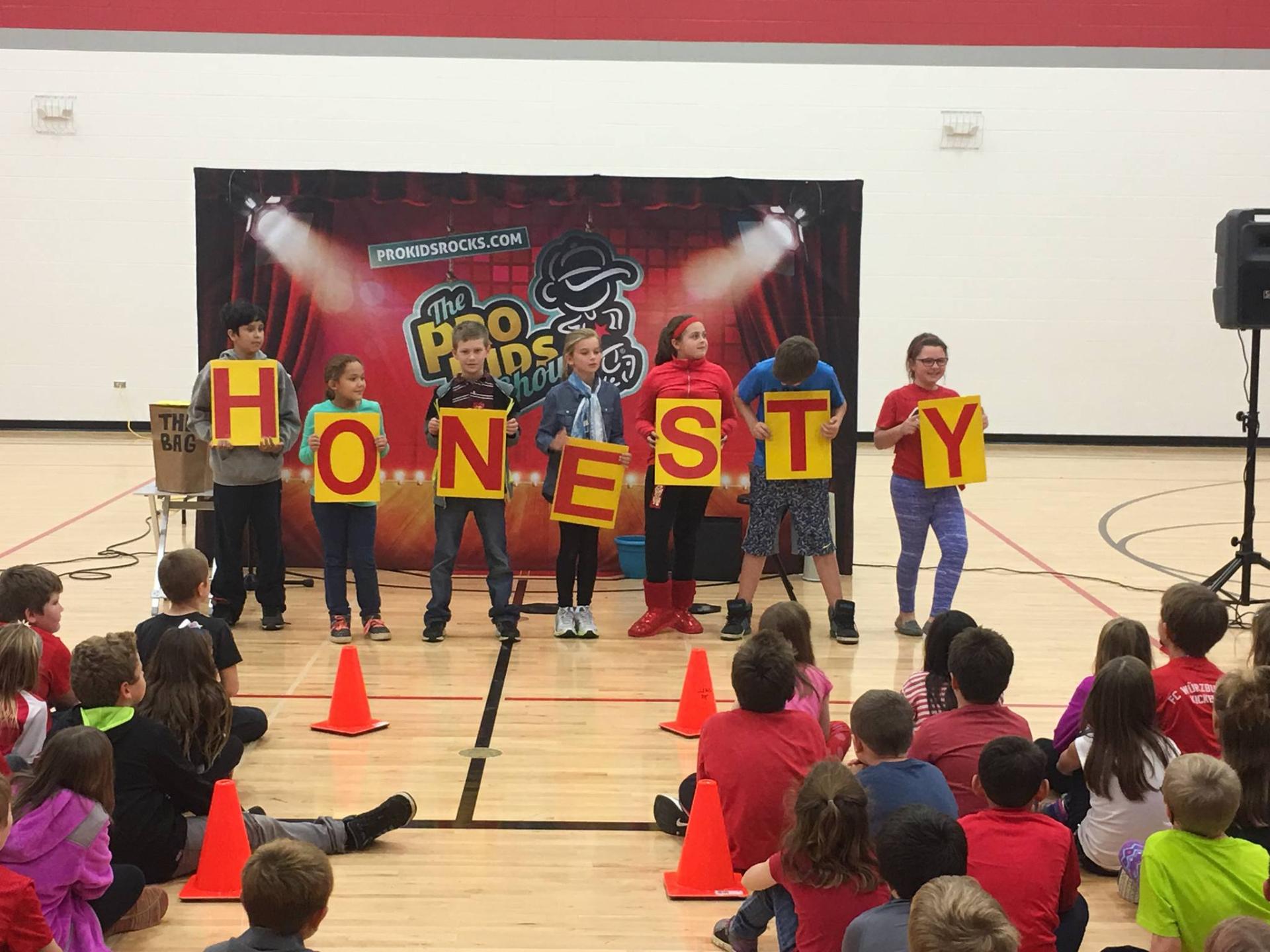 Tim on stage during a Pro-Kids assembly moment tied to character education